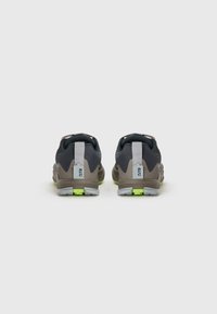 Un paio di sneakers grigie e nere con accenti verde neon viste da dietro, caratterizzate da tasselli grigi con l'etichetta "GTR."