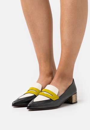 Sorte læderloafers med spids snude, med gule og hvide detaljer, en lille blokhæl med et tekstureret mønster og en glat finish.