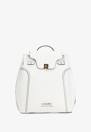 Sac à dos en cuir blanc au design structuré, avec des coutures noires, un fermoir doré et une poignée supérieure. Il présente un rabat avant et des détails de logo.