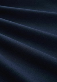 Tamsiai mėlyna medžiaga su glotnia tekstūra, pasižyminti švelniais sraigtiniais raukšlėmis ir nuosekliu audimu. Be raštų ar elementų.