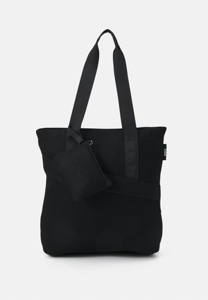 Sac cabas en filet noir avec deux bretelles d'épaule, comprenant une petite pochette détachable, une surface texturée et un marquage minimaliste sur le côté.