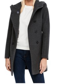 Mørkegrå uldfrakke med hætte, dobbeltknaplukning, store knapper og sidelommer. Bæres over en hvid struktureret top og blå jeans.