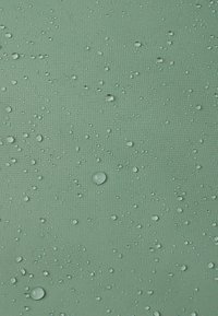 Tissu vert texturé avec des gouttelettes d'eau de différentes tailles, présentant une surface lisse et une finition mate.