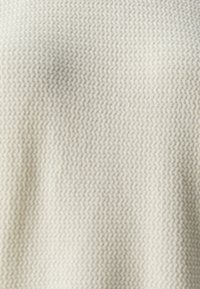 Textured fabric in a light cream color, showcasing a woven pattern with a soft, smooth texture.