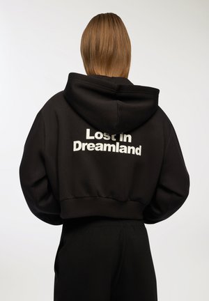 Felpa nera corta realizzata in tessuto morbido, con cappuccio regolabile e testo bianco "Lost in Dreamland" sul retro.