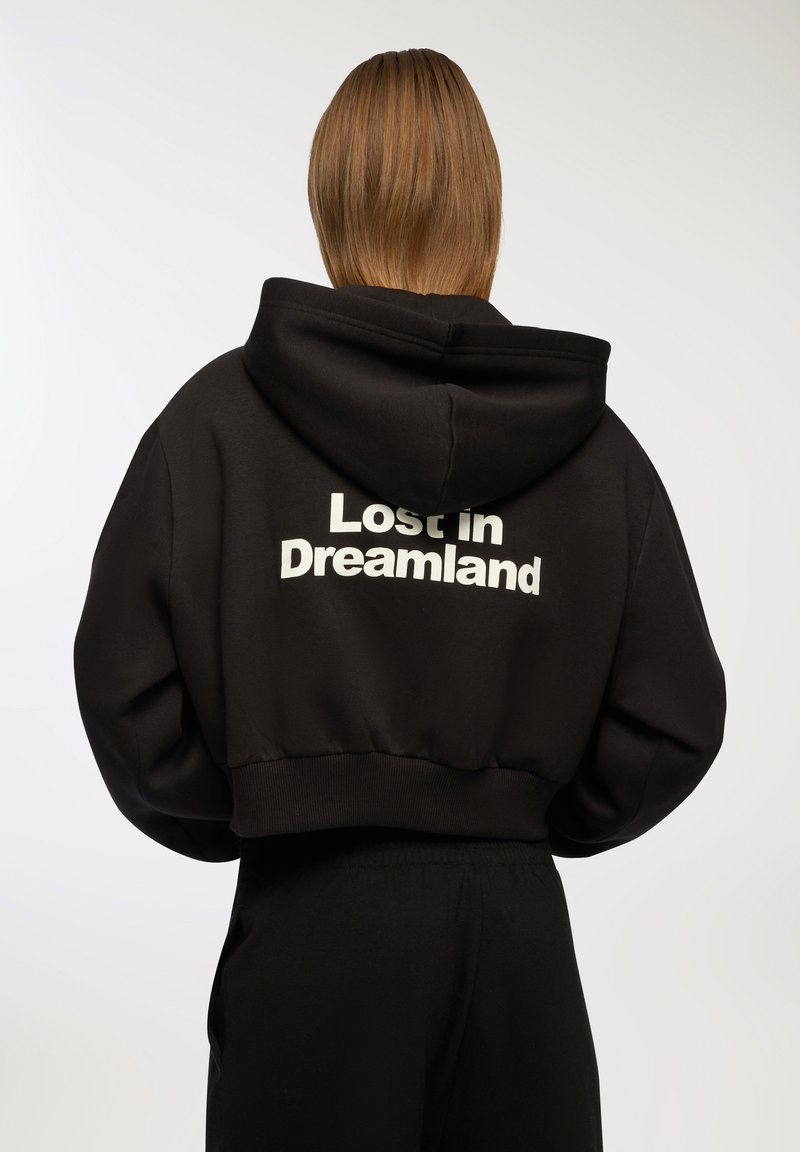 Felpa nera corta realizzata in tessuto morbido, con cappuccio regolabile e testo bianco "Lost in Dreamland" sul retro.