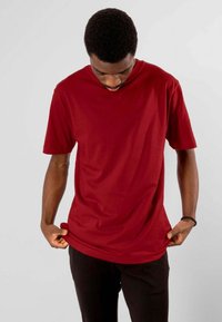 Rød bomulds T-shirt med rund hals og korte ærmer; let løs pasform. Stoffet ser blødt ud med minimal tekstur.
