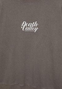 Szürke pulóver, fehér grafikával, amelyen a "Death Valley" felirat olvasható, alatta pedig a "MENEKÜLJ A VÁROSBÓL, TALÁLD MEG A SZABADSÁGOT" szlogen. Puha tapintású.