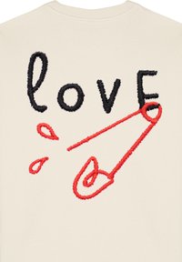 Felpa beige con testo ricamato in nero e rosso che scrive "love", con un grande dettaglio in forma di spillo di sicurezza rosso e dettagli di spruzzo.