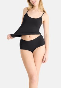 Svart camisole med tunna axelremmar och matchande högmidjade trosor. Båda plaggen har ett slätt, elastiskt tyg och minimala sömmar.
