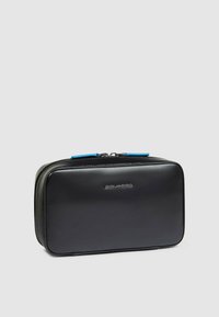 Bustina cosmetica in pelle nera di forma rettangolare, con cerniera blu e marchio discreto sulla parte anteriore. Texture liscia.