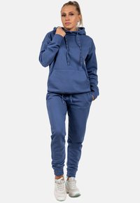 Set di felpa con cappuccio e pantaloni jogging realizzato in tessuto morbido. La felpa presenta un cappuccio con lacci e una tasca frontale; i pantaloni jogging hanno polsini elastici e una vestibilità comoda.
