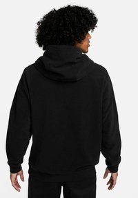 Schwarzer Kapuzenpullover aus weichem Stoff mit langen Ärmeln und lockerer Passform. Die Rückseite hat ein schlichtes Design mit einer geräumigen Kapuze.