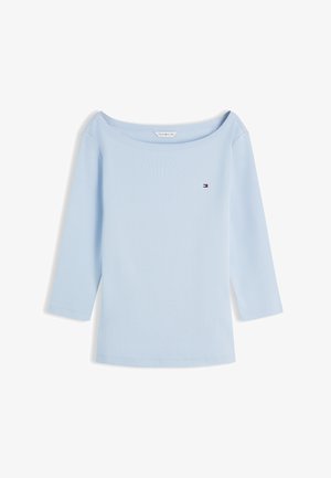 Haut féminin bleu clair à manches longues avec un large col rond échancré et un petit logo Tommy Hilfiger sur le côté gauche de la poitrine.