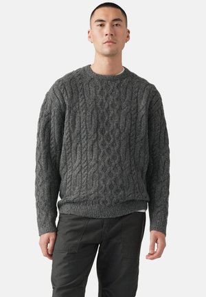 Suéter gris de punto trenzado con cuello redondo acanalado y puños. Confeccionado en un tejido grueso y texturizado, presenta un corte holgado y forma cuadrada.