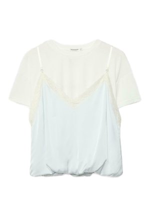 T-shirt blanc à manches courtes superposé avec un caraco en satin bleu clair orné de dentelle et doté de fines bretelles réglables.