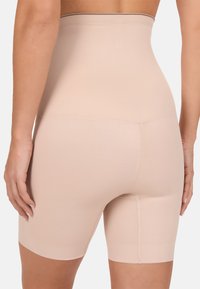 Shorts modellanti beige a vita alta realizzati in materiale elastico. Presentano un design senza cuciture, lunghezza a metà coscia e una sottile texture a coste.