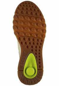 Sole of a shoe featuring a brown rubber material with circular and teardrop patterns; green accent with branding in the center.