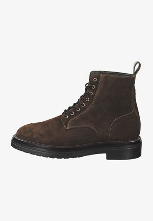 Braune Wildleder-Stiefelette mit runder Spitze, schwarzen Schnürsenkeln, Metallösen und einer strukturierten Gummisohle. Mit einer Schlaufe auf der Rückseite für ein einfaches Anziehen.