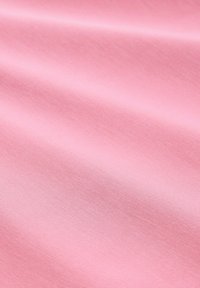 Lichtroze stof met een gladde textuur, voorzien van een zichtbaar geweven patroon. Het materiaal valt soepel en weerkaatst subtiel het licht over het oppervlak.