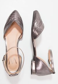 Chaussures à talons hauts en bronze métallique avec bout pointu, design plissé à l'avant, bride à la cheville et un talon carré modeste. Texture lisse.