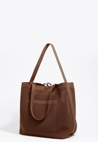 Borsa a rete marrone con base solida, due manici lunghi e una tasca esterna. Presenta un motivo testurizzato per la traspirabilità.