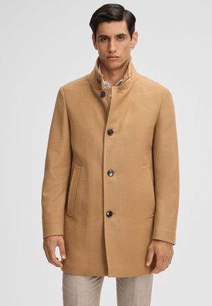 Beige wollen jas met een hoge kraag, vijf knopen, twee voorzakken en een rechte snit. De stof heeft een gladde textuur en een goed aansluitende pasvorm.