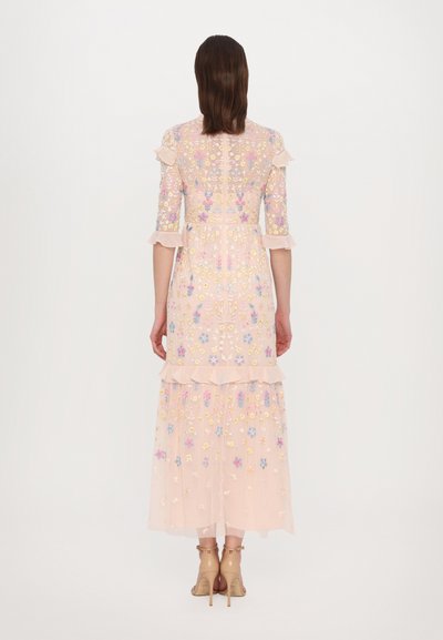 Lichtroze, gelaagde maxidress gemaakt van doorzichtige stof met kleurrijke bloemenborduursels. Heeft ruches mouwen en een corsage.