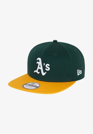 Gorra snapback verde y amarilla con logo blanco de "A's", visera plana y tejido texturizado. Incorpora una correa ajustable para el tamaño.