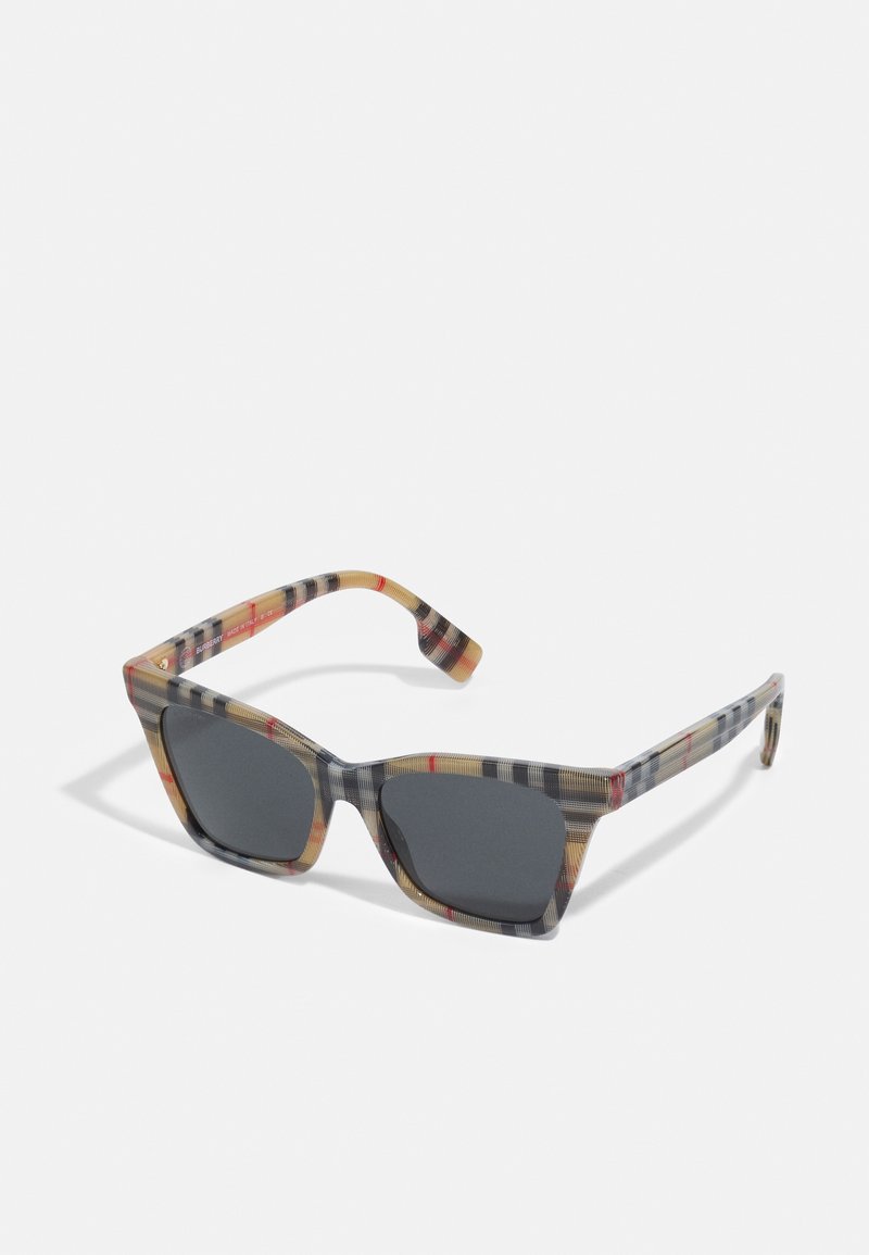 Schwarz-weiße, karierte Sonnenbrille mit rechteckigen, schwarzen Gläsern, aus leichtem Kunststoff mit einem Mix aus Beigetönen, Schwarz und roten Akzenten.