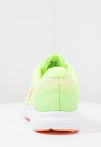 Baskets de course vertes en mesh avec une surface texturée, un talon renforcé et une semelle intermédiaire blanche. Présente un logo accent rose sur le côté.