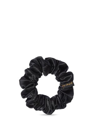 Chouchou en soie noire avec texture de tissu froncée et une petite étiquette portant la mention "le silque" sur fond blanc.