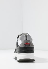 Grå läder- och mockaskor med en vit mellansula och svart sula. Har en dragkedja och en röd logotypaccent på hälen.