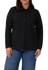 Zwarte langslavige shirt met een button-down kraag en een voorpats, met zwarte knopen en een soepele katoenen textuur. Gecombineerd met blauwe spijkerbroeken.