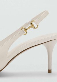 White high-heeled sandal with a pointed toe, leather material, slingback strap featuring a gold circular hardware detail.