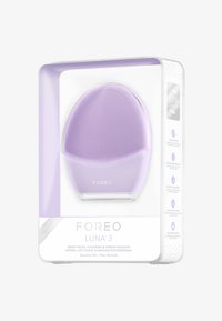 Dispositivo di pulizia LUNA 3 in silicone lavanda, forma ovale con superficie testurizzata, presentato in una scatola trasparente con dettagli del prodotto sulla parte anteriore.