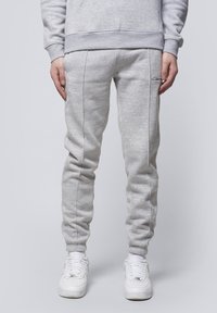 Gray sweatpants in a tapered design, featuring ribbed cuffs and side seams, paired with white sneakers. Soft texture and casual fit.