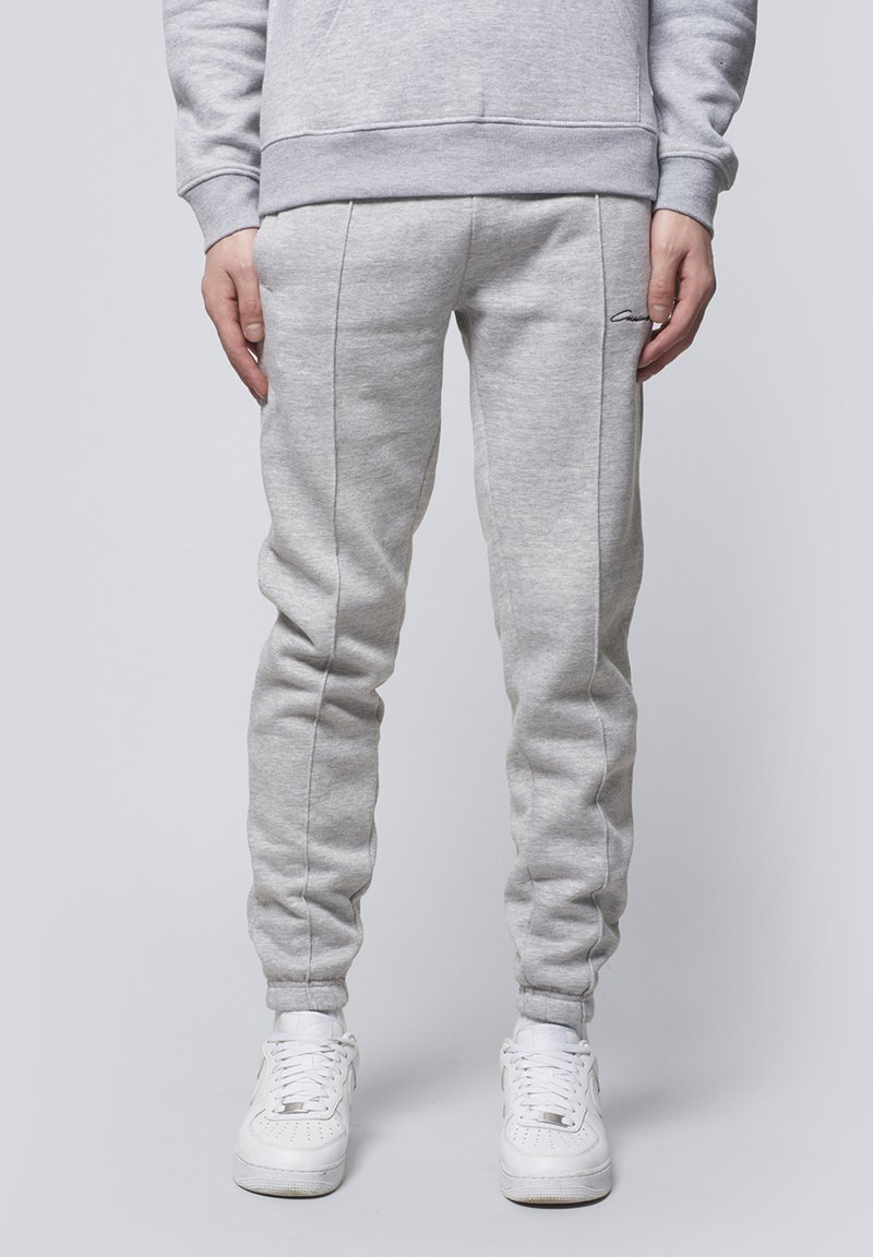 Gray sweatpants in a tapered design, featuring ribbed cuffs and side seams, paired with white sneakers. Soft texture and casual fit.