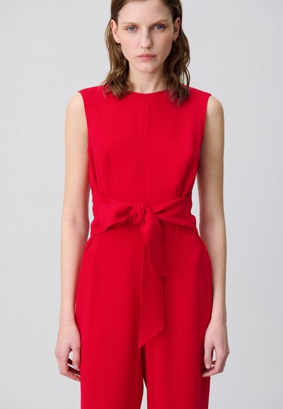 Mono sin mangas rojo con un nudo en la cintura. Tela suave, diseño minimalista y una silueta recta que destaca un color audaz.