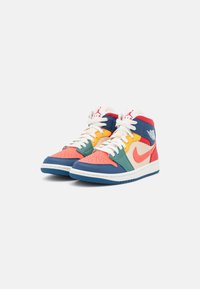 Un par de zapatillas de baloncesto Nike Air Jordan de caña alta en varios colores, con detalles en naranja, azul, verde, amarillo, rojo y blanco, y cordones blancos sobre un fondo blanco.