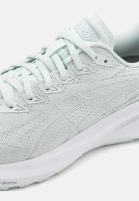 Lyseblå joggesko med et teksturert mesh-overdel og hvit såle, flate lisser, forsterkede snøringer og subtile merkevaredetaljer.