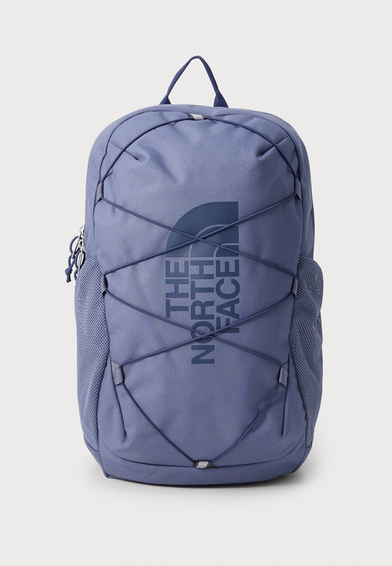 Purple fabric backpack featuring a prominent logo, elastic bungee design on the front, and mesh side pockets for storage.