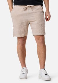 Shorts en coton texturé beige avec taille élastique et cordon de serrage, dotés de poches latérales et d'une finition ourlée.