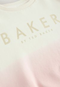 Lengvas džemperis su grietinėlės ir minkštos rožinės spalvos perėjimu. Pasižymi aukso įspaustu tekstu: "BAKER by TED BAKER", kuris aiškiai matomas. Raukšlėta apykaklė.