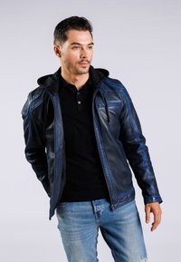 Niebieska skórzana kurtka z kontrastującym czarnym kapturem, z zamkiem z przodu, akcentami na ramionach i dopasowanym krojem, noszona na czarnej koszuli.