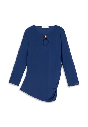 Long-sleeve top in deep blue fabric, featuring a scoop neckline with a round cutout and a decorative gold accent at the neck. Soft texture, asymmetric hem.