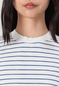 T-shirt w paski z bawełny z okrągłym, lekko falbaniastym wykończeniem dekoltu. Wykonany z białej tkaniny w niebieskie poziome paski. Teksturowane wykończenie.