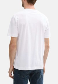 T-shirt en coton blanc à manches courtes, col rond et ourlet droit. Présente une coupe classique sans logos ni motifs visibles.