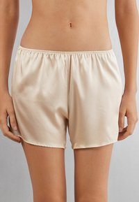Satinbeige shorts med elastisk midja, med en slät textur och en längd till mitten av låret, designade för komfort och enkel att bära.