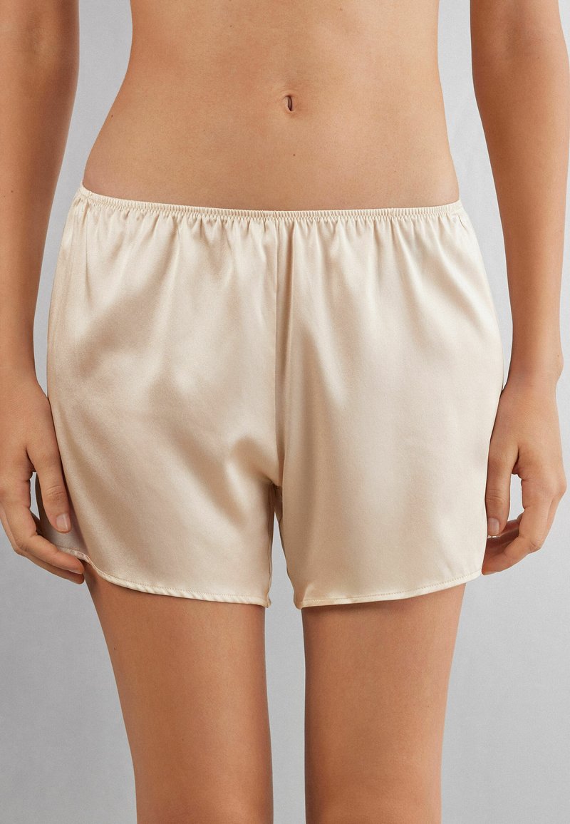 Satinbeige shorts med elastisk midja, med en slät textur och en längd till mitten av låret, designade för komfort och enkel att bära.